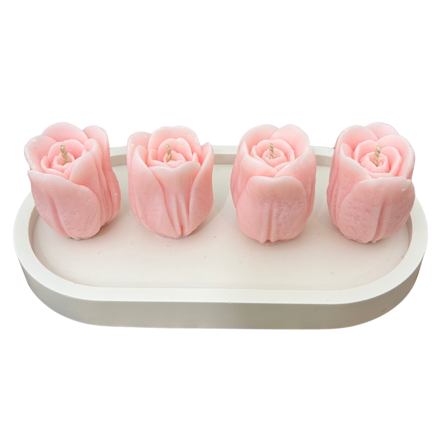 Four pink tulip-shaped candles on a white tray with a white background