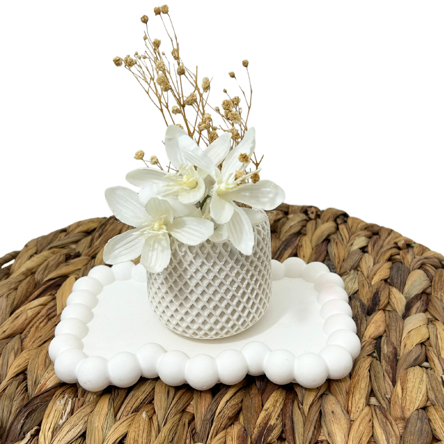 Decorative flower arrangement on a textured white base with a woven brown mat background