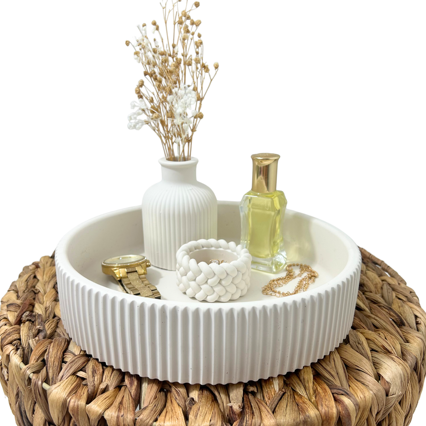 Decorative setting with a white bowl, vase, and bottle on a woven surface.