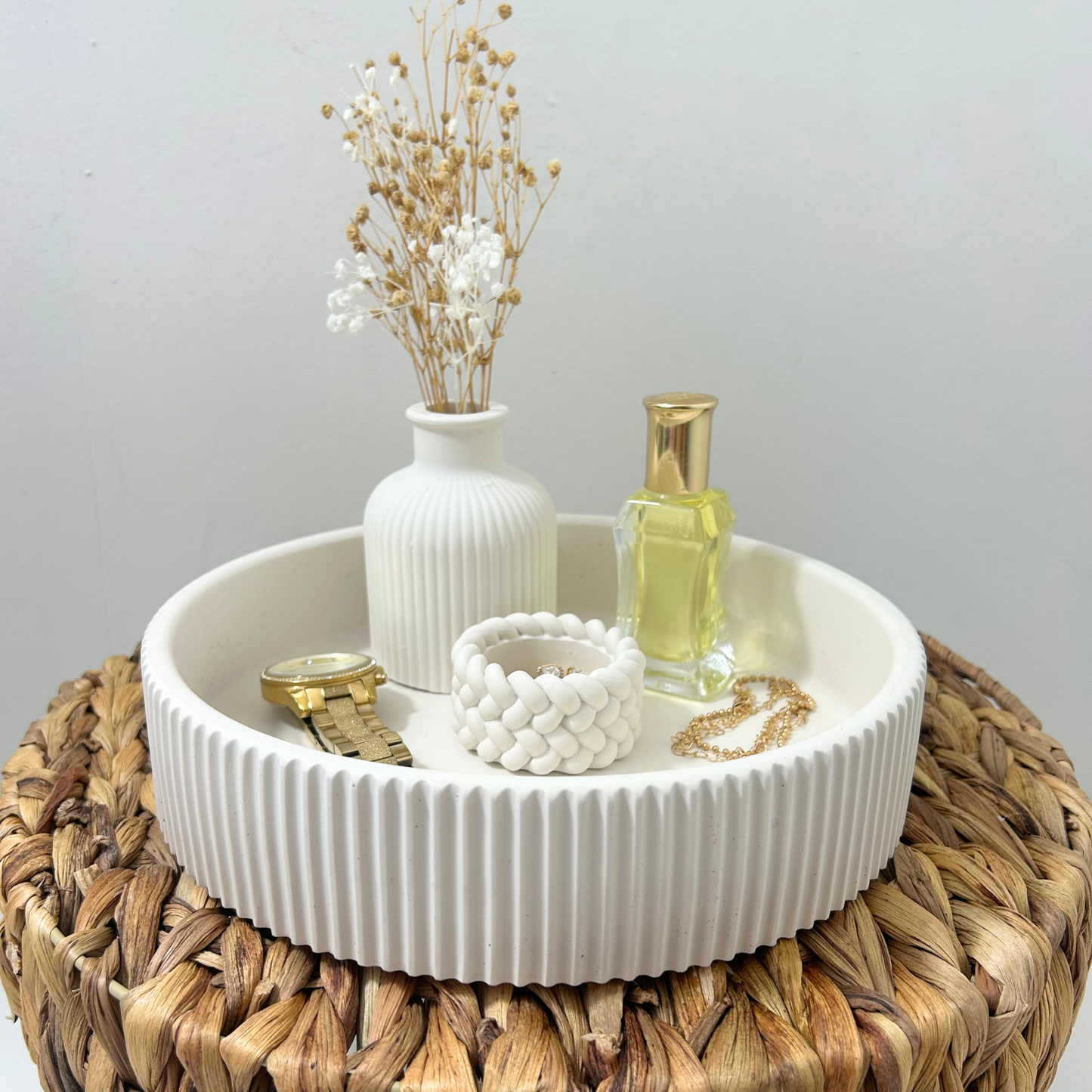 Decorative items including a vase with dried flowers, a bottle, and jewelry on a white bowl.