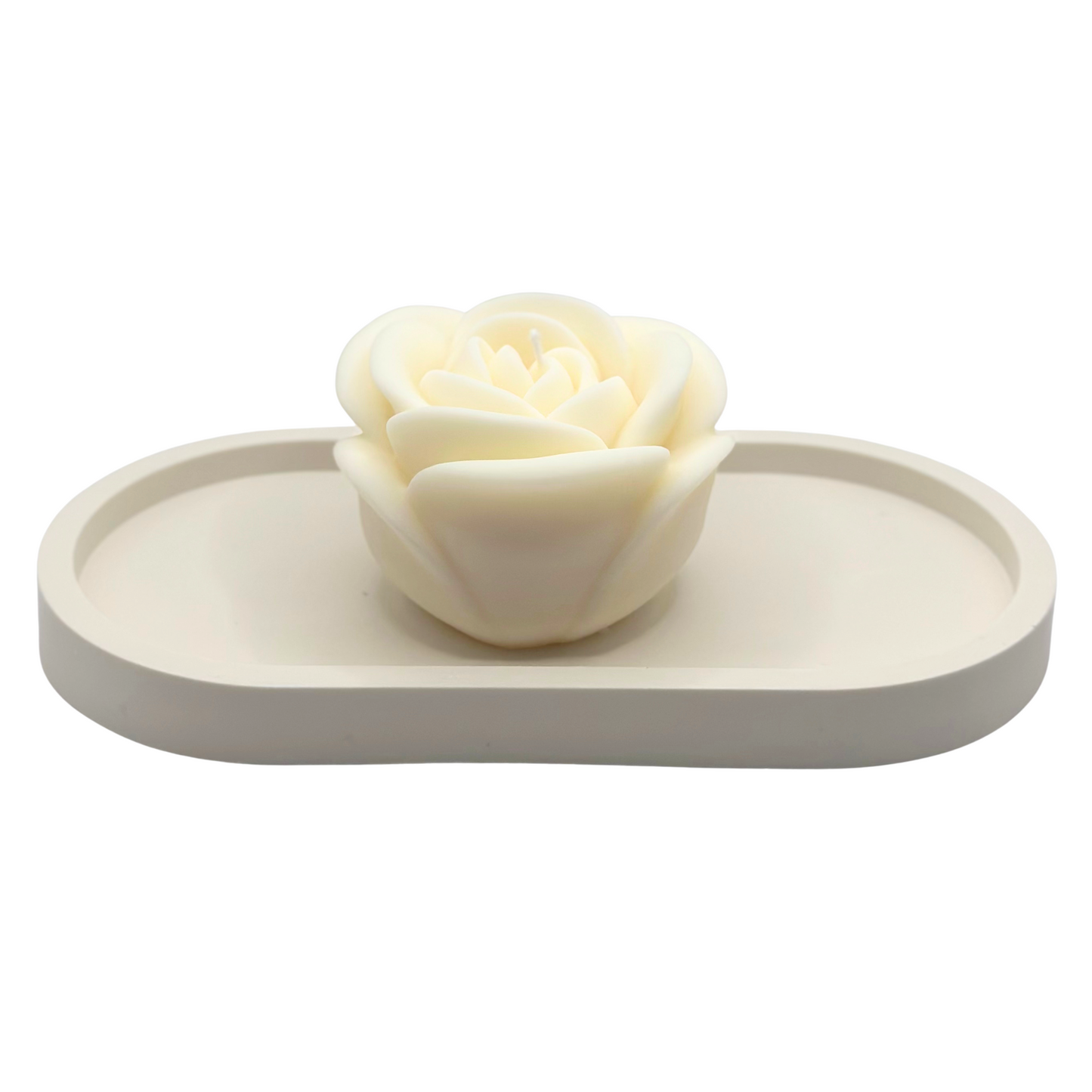 White rose-shaped candle on a rectangular white dish against a white background