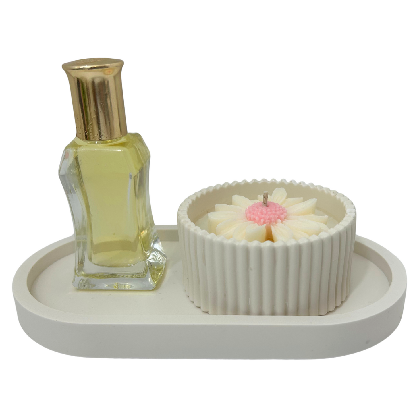 Small bottle of perfume and a decorative daisy candle on a white tray with a white background