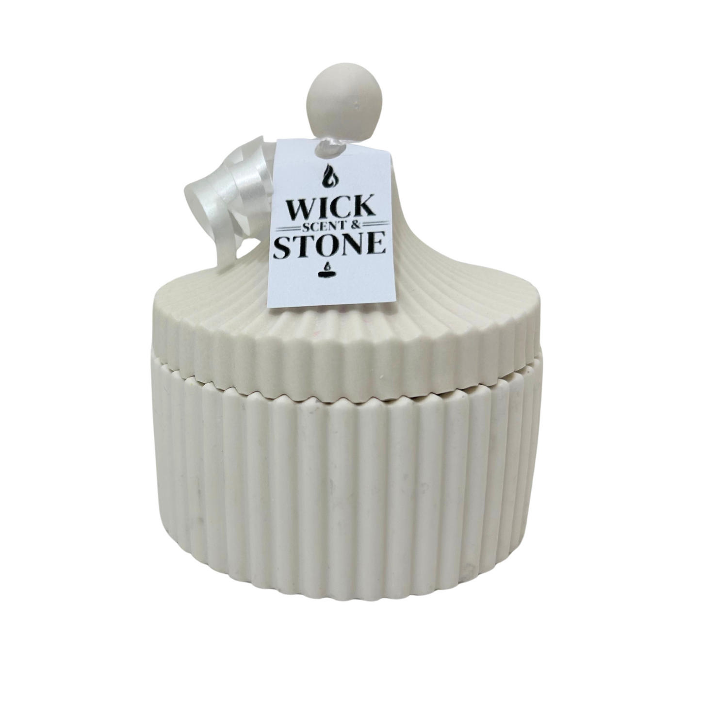 Jesmonite ribbed container with a tag labeled 'Wick Scent & Stone' on a white background