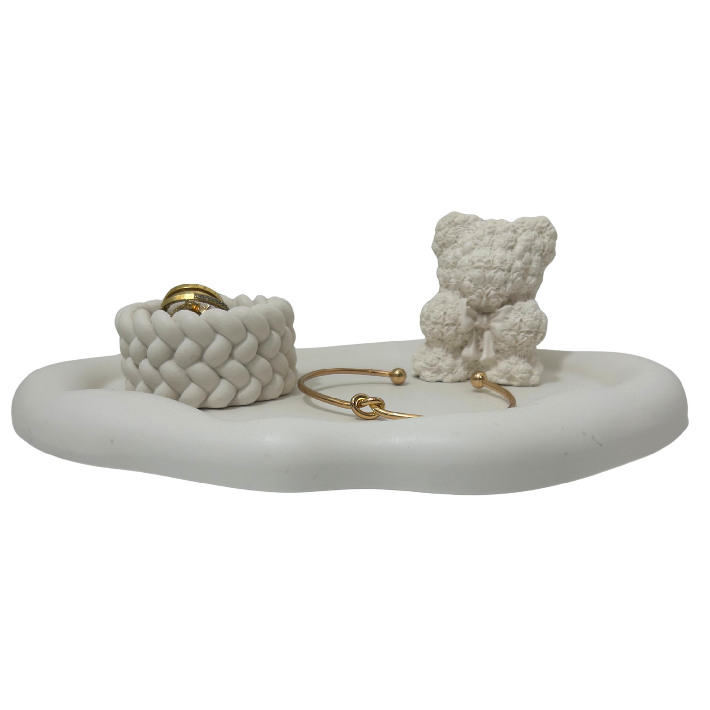 White marble jewelry holder with woven basket, gold bracelets, and a small white bear figurine on a white background.