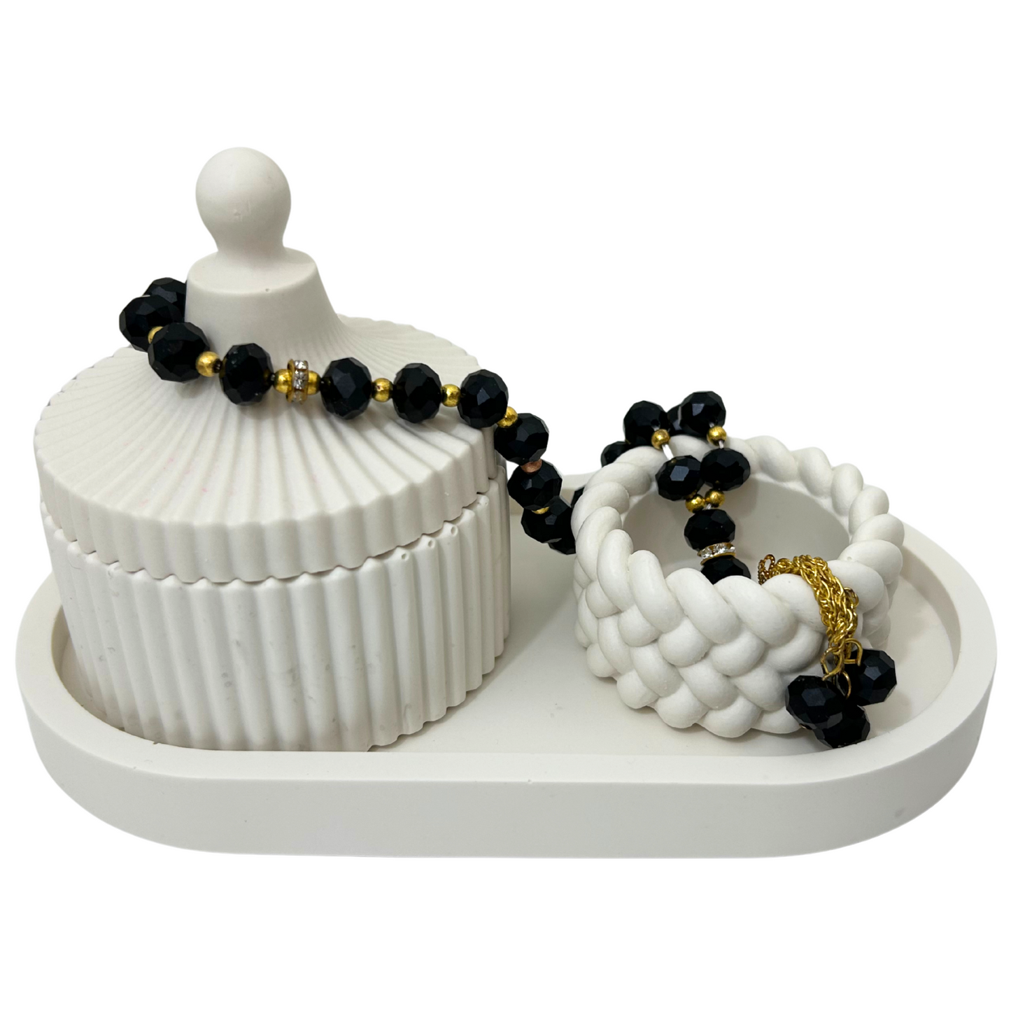 Jesmonite stone jewelry holder with black and gold beaded bracelets on a white background