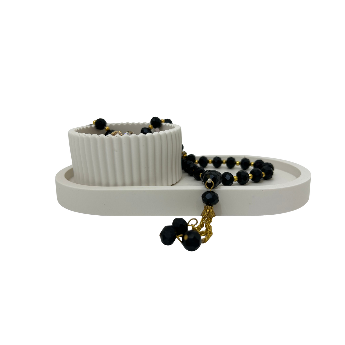 White jewelry stand with a bowl and black beaded necklace on a white background