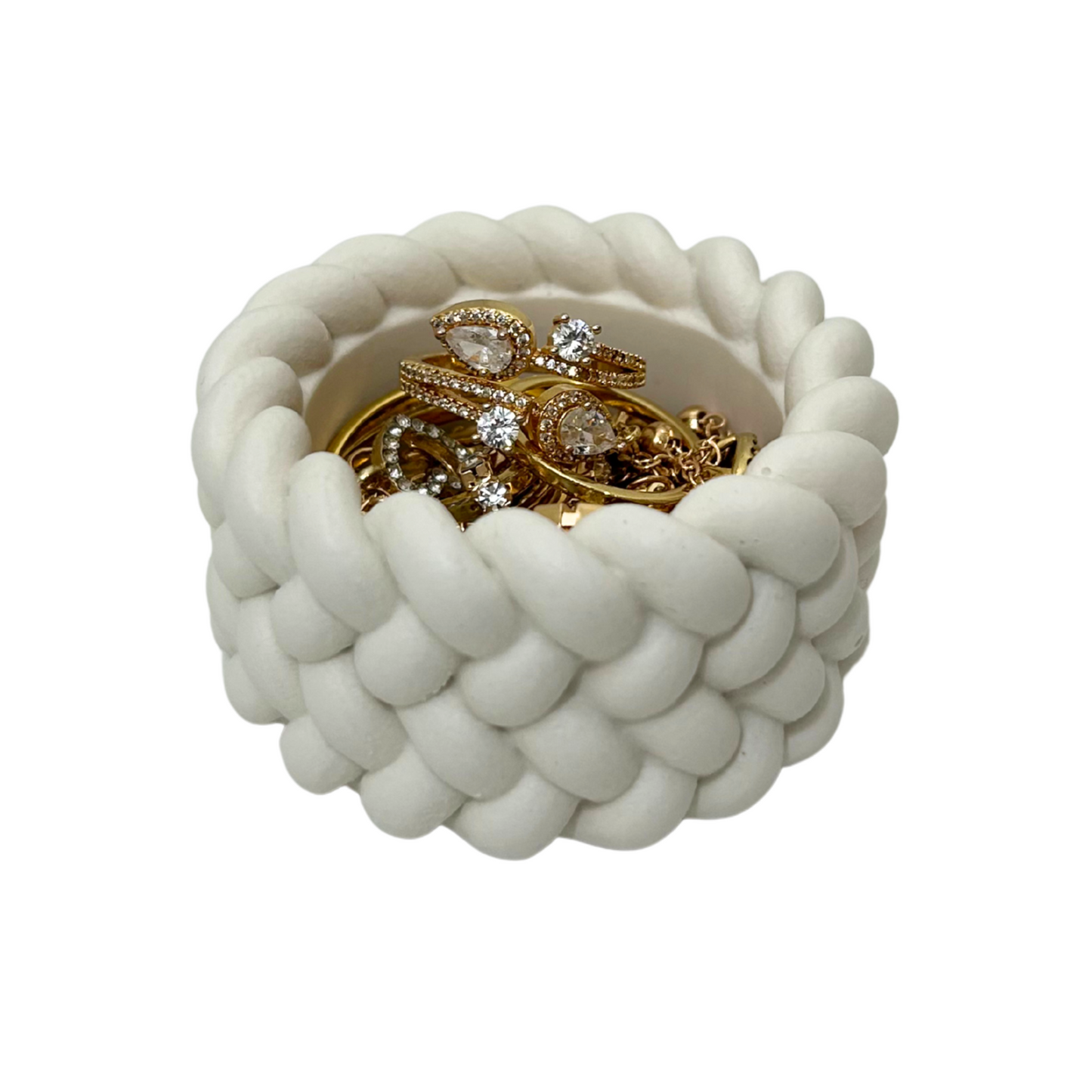 White woven trinket jar with gold jewelry on a white background