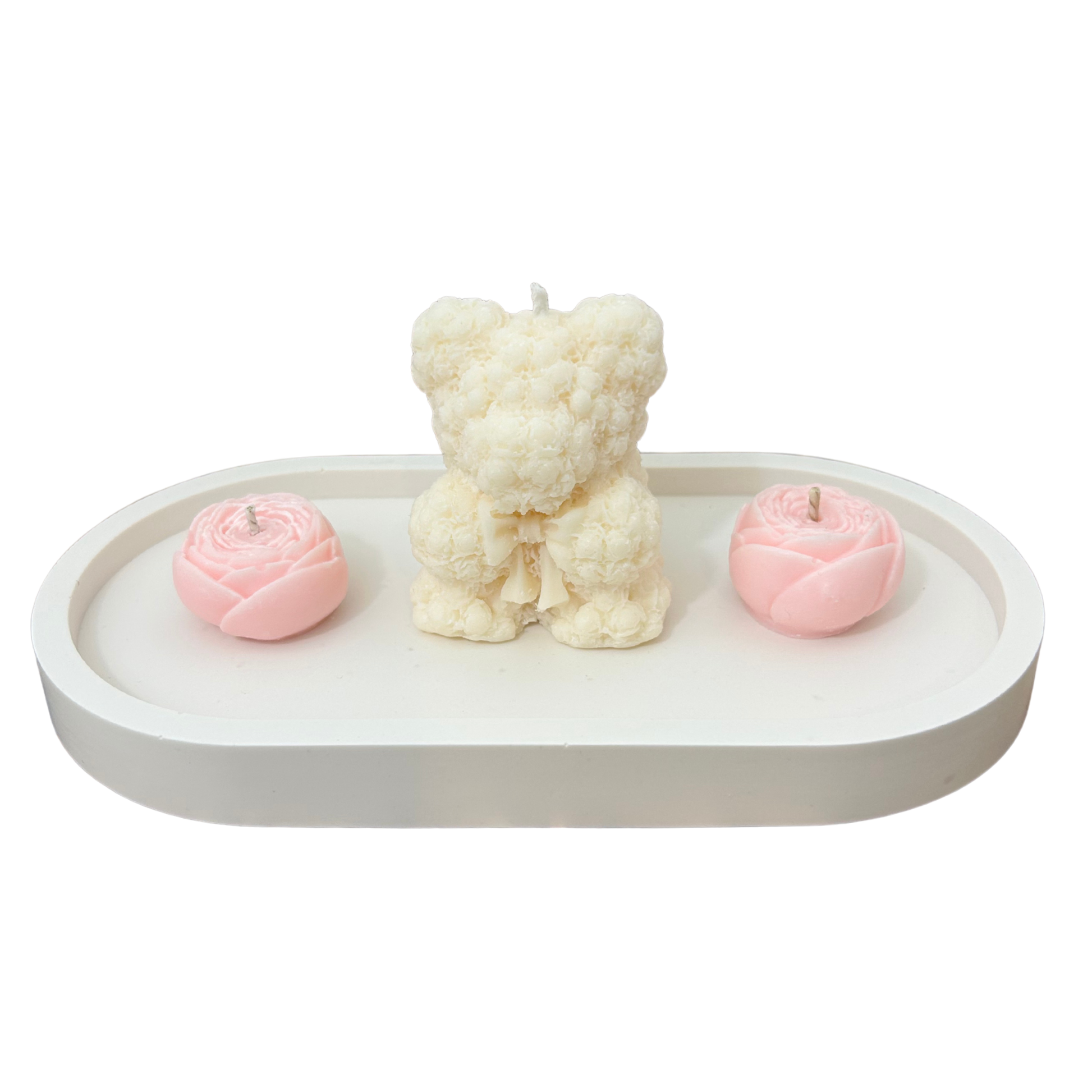 Three candles shaped like a bear and flowers on a white tray with a white background