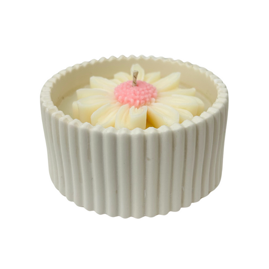 Candle with a daisyl design in a ribbed container on a white background